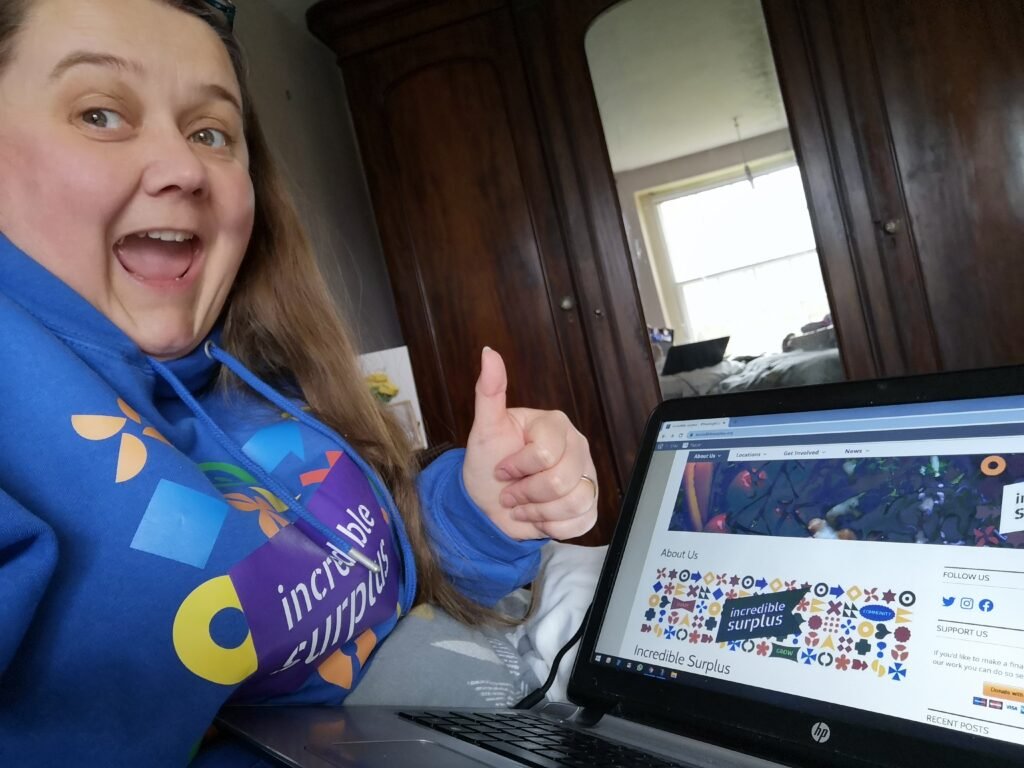 Amber sat with her laptop, showing the Incredible Surplus site at launch, while wearing and Incredible Surplus branded hoodie